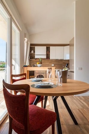 A dining area with a round table, chairs, and a kitchen in the background. - Sardinian Pearl Retreat-Beach House (Cagliari)