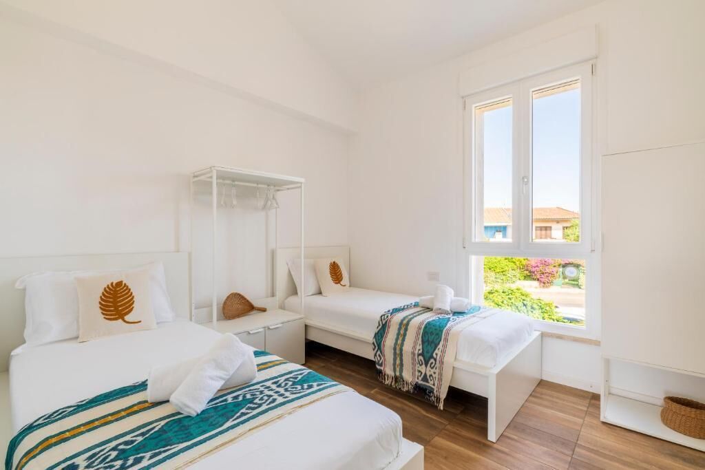 Ein Zimmer mit zwei Betten, einem Fenster und Blick auf Grünfläche.