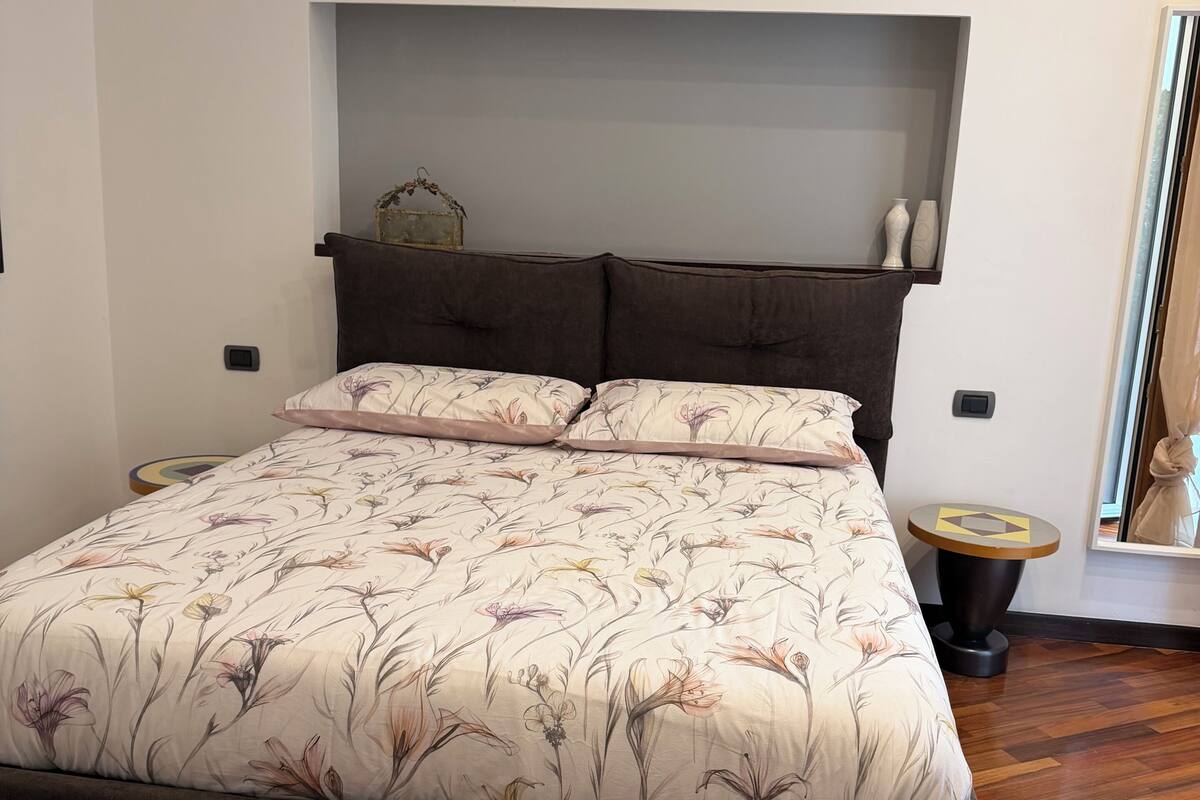 Une chambre à coucher comprenant un lit, une tête de lit, une table de chevet et un miroir.