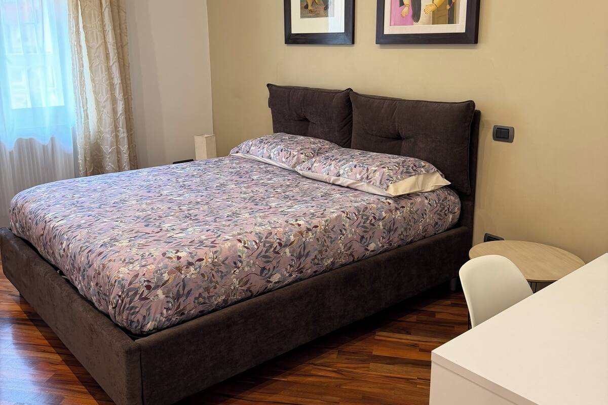 Une chambre à coucher avec un lit, un bureau et deux tableaux encadrés accrochés au mur.