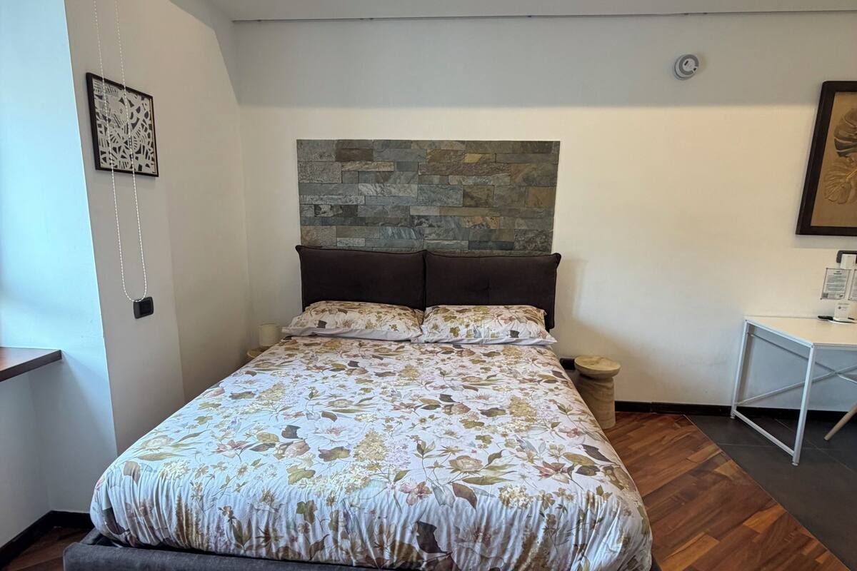 Une chambre à coucher comprenant un lit, une tête de lit, une table de chevet et une étagère, ainsi qu’une œuvre d’art accrochée au mur.