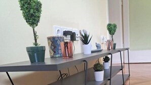 Una habitación moderna con piso de madera, una mesa metálica gris con estantes y varias plantas en macetas.