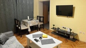 Una sala de estar con televisor, mesa de comedor y sofá.