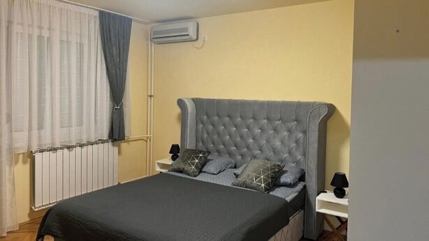 Un dormitorio con una cama grande, una mesita de noche, una lámpara y un equipo de aire acondicionado.