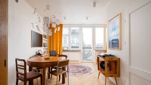A dining area with a round table, chairs, a rug, a record player, and a painting on the wall. - Wilcza Retro – City Center, Balcony – by Rentujemy (Warszawa)