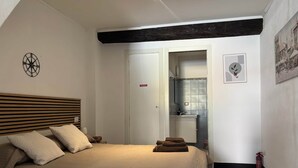 Quarto com cama, cabeceira, porta, banheiro com pia e um extintor de incêndio.