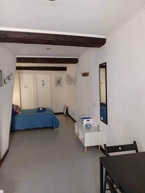 Una habitación con cama, una mesita, un espejo y una puerta.