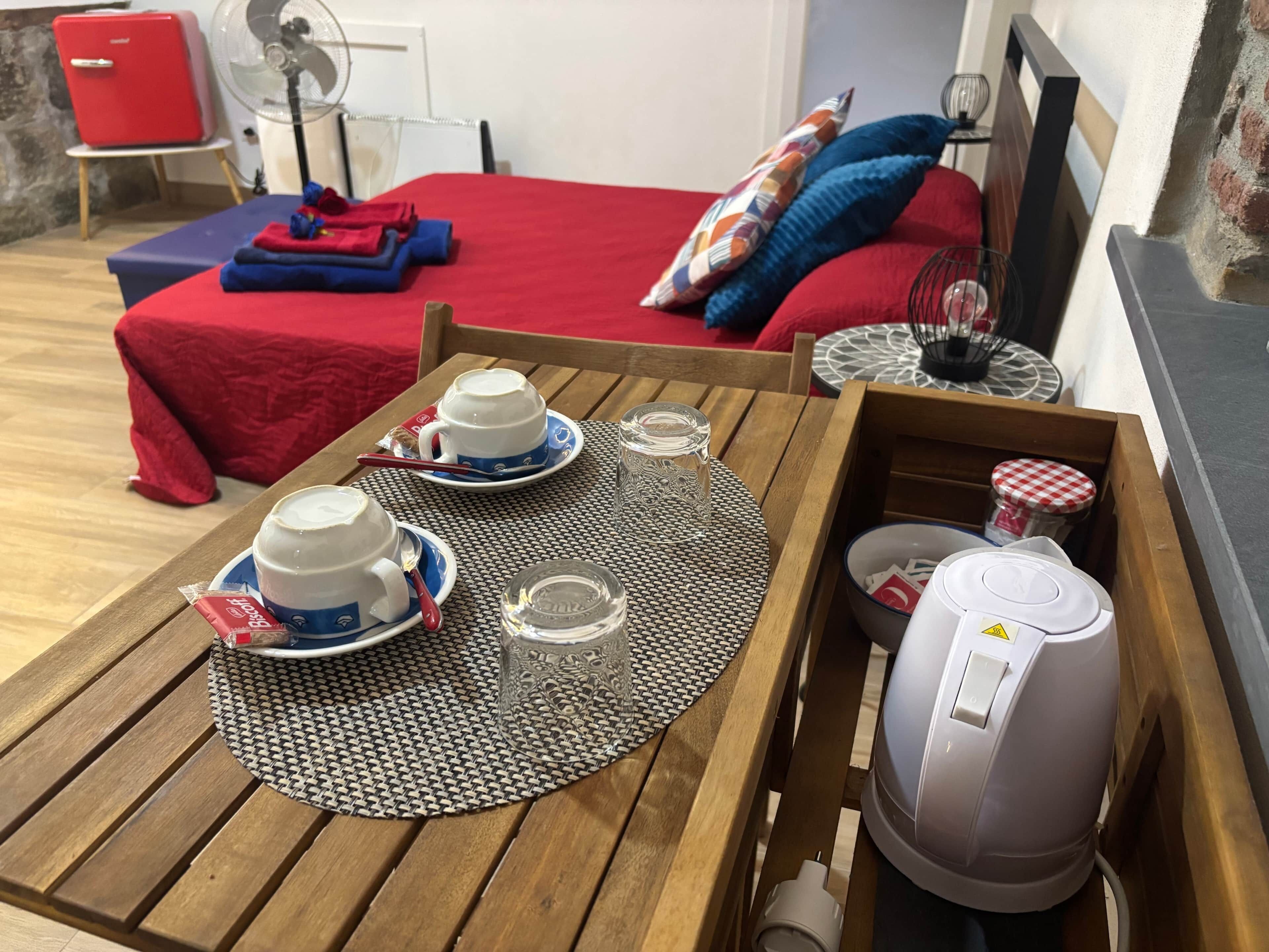 Una mesa de desayuno ordenada con dos tazas, un vaso y una tetera, sobre un mantel tejido.