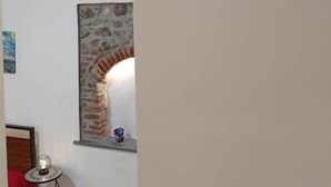 Una habitació amb una llar de foc de rajola, un mirall rodó i una decoració mural.