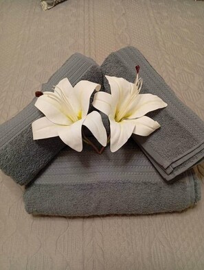 Ein Stapel grauer Handtücher mit zwei weißen Blüten darauf.