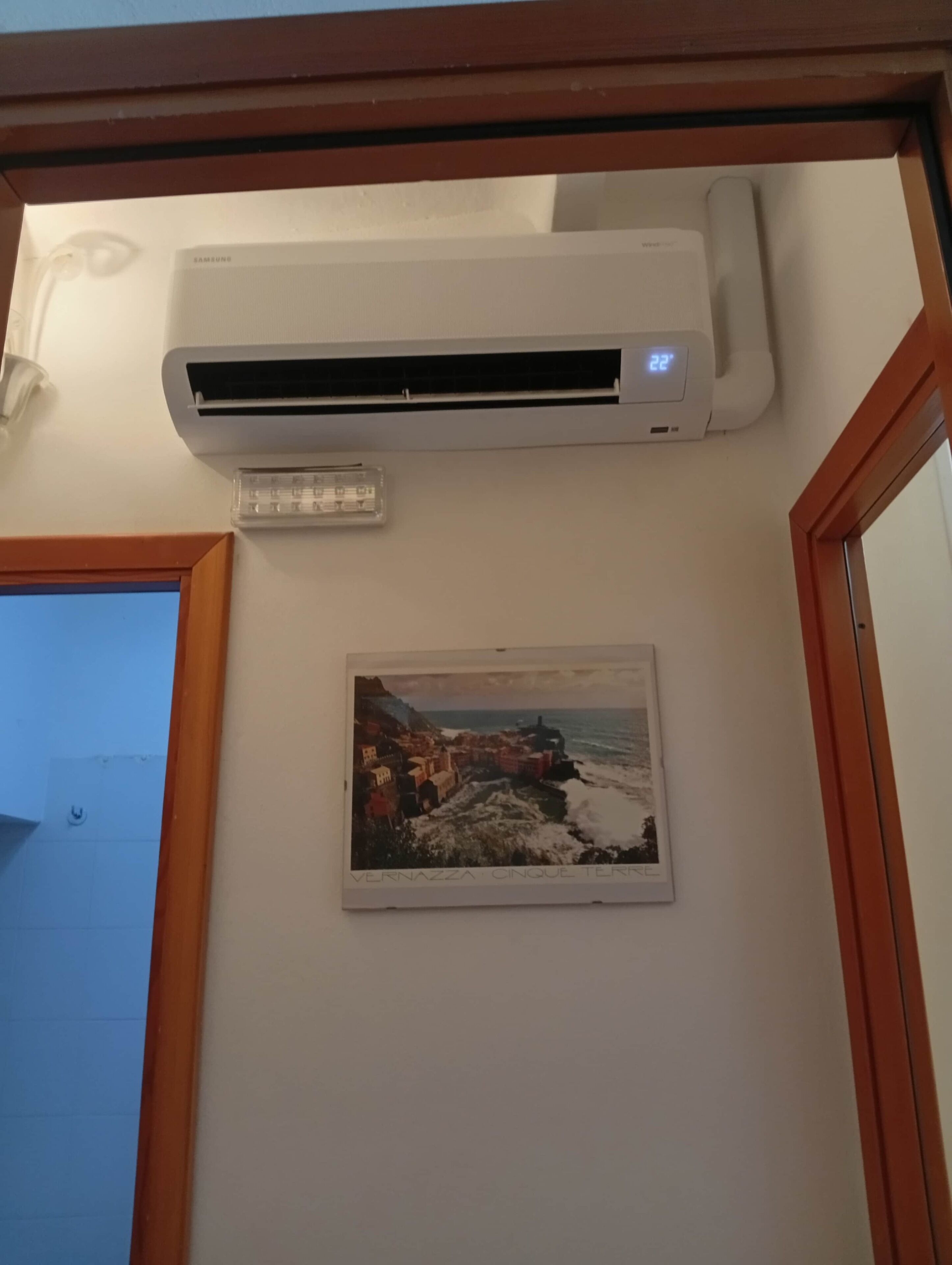 Un condizionatore d'aria fissato al muro con un quadro incorniciato sotto.