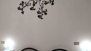 A bed with two pillows, a wall decoration, and bedside tables with lamps. - Il Grifo Apartment (Vernazza)