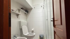 A bathroom with two toilets, a bidet, a glass shower enclosure, and a trash bin. - Il Grifo Apartment (Vernazza)