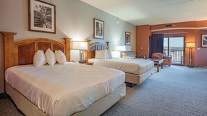 Een hotelkamer met twee bedden, een bureau, een stoel en een balkon met uitzicht.