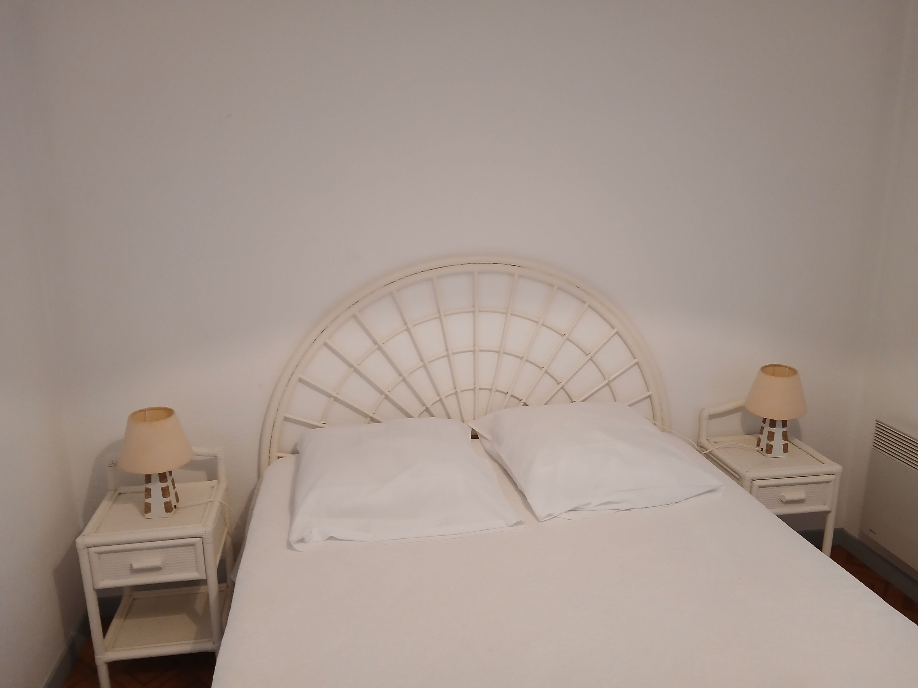 A bed with a white headboard and two bedside tables with lamps.