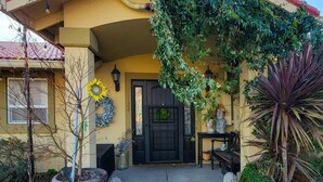 A house with a black door, a number '122' on the wall, and a porch with plants and a bench. - Dream House - three bedroom, three in a half baths on Paschal Vineyard (Talent)