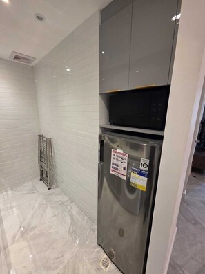 A modern kitchen with white subway tiles, a stainless steel refrigerator, and a microwave. - Ultralux Suite 1 Bedroom in BGC (Taguig)
