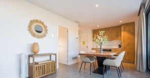 Eine moderne Küche mit Holzausbau, einem Esstisch mit Stühlen, einem dekorativen Spiegel und einer Vase mit Blumen.