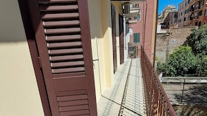 A narrow balcony with a metal railing, a door with brown shutters, and a view of adjacent buildings. - Pigneto new collection 1 (Rome)
