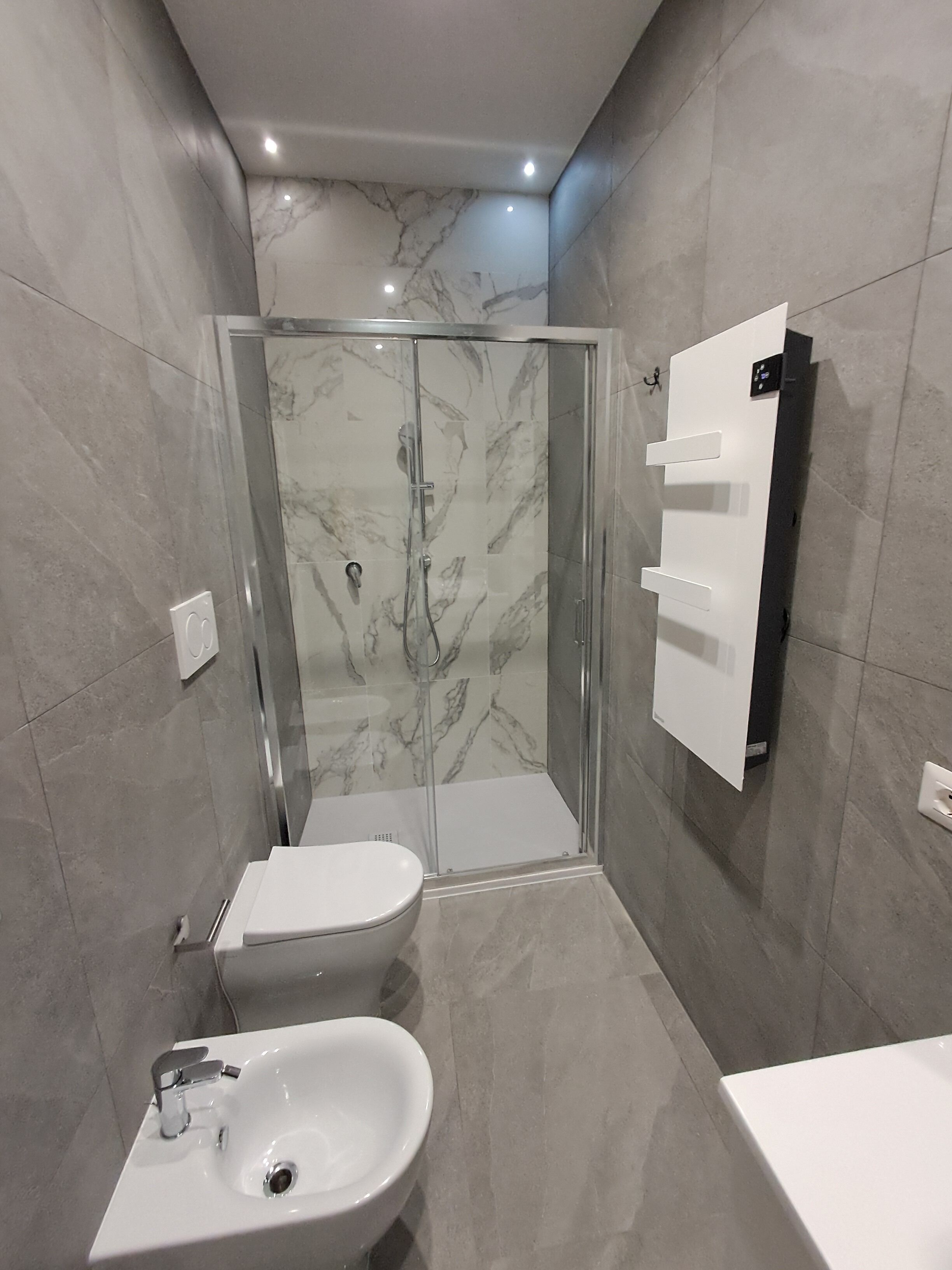 A modern bathroom with a glass-enclosed shower, a white toilet, and a sink.