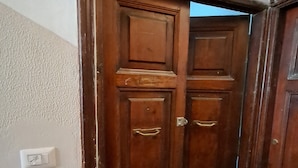 A wooden door with a handle and a light switch on the wall. - Pigneto new collection 1 (Rome)
