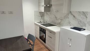 A compact kitchen with a white countertop, a built-in oven, and a marble backsplash.