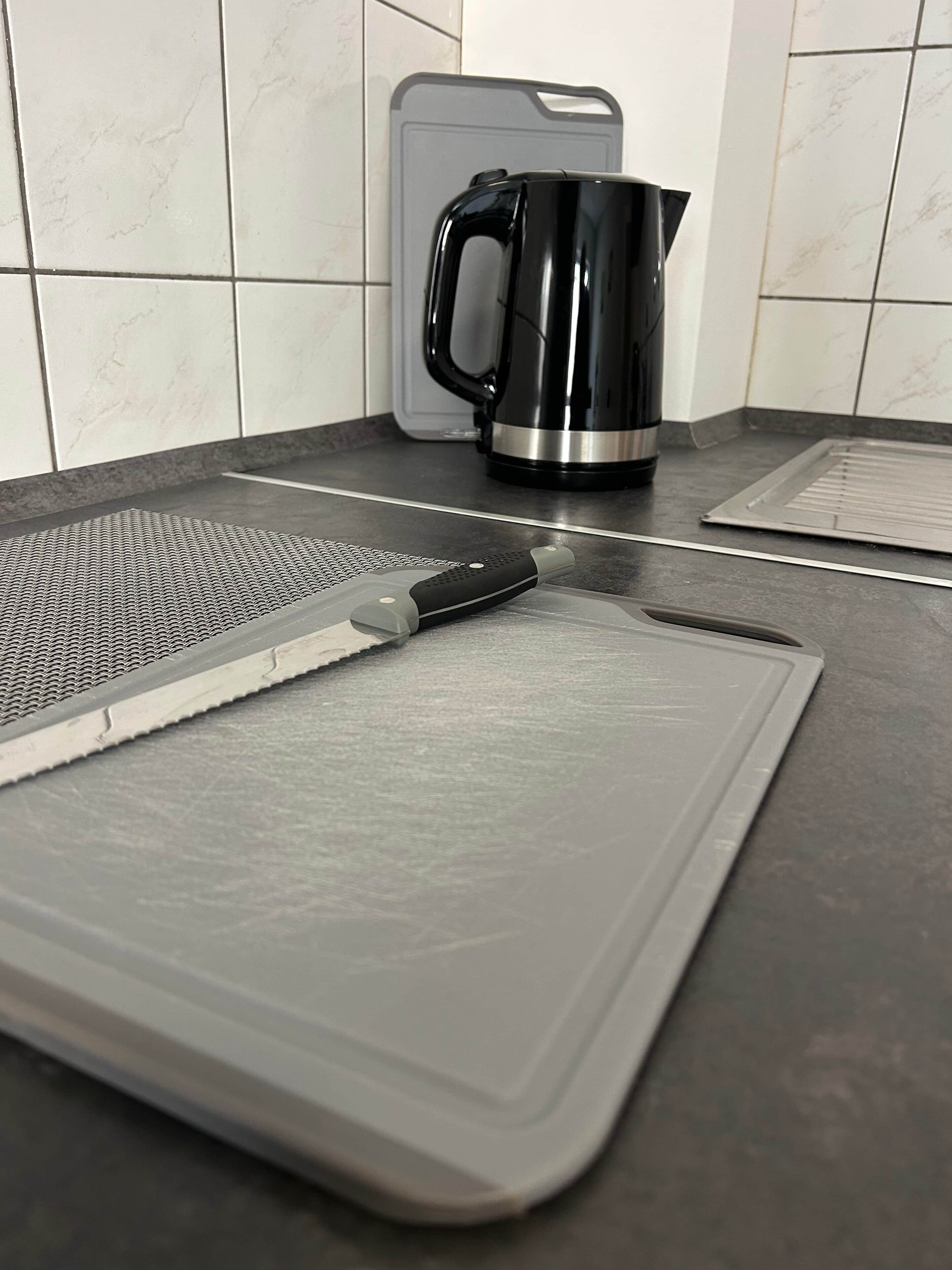 Een aanrecht met een snijplank, een mes en een koffiezetapparaat.