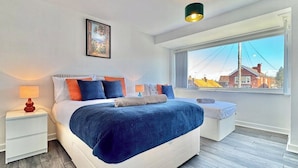 A bedroom with a bed, bedside tables, a window with a view, and a painting on the wall. - Modern 3 Bedroom Home | 4 Beds | Private Parking (Doncaster)
