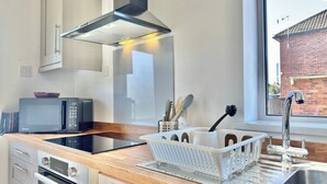 A modern kitchen with a microwave, stove, and sink. - Modern 3 Bedroom Home | 4 Beds | Private Parking (Doncaster)