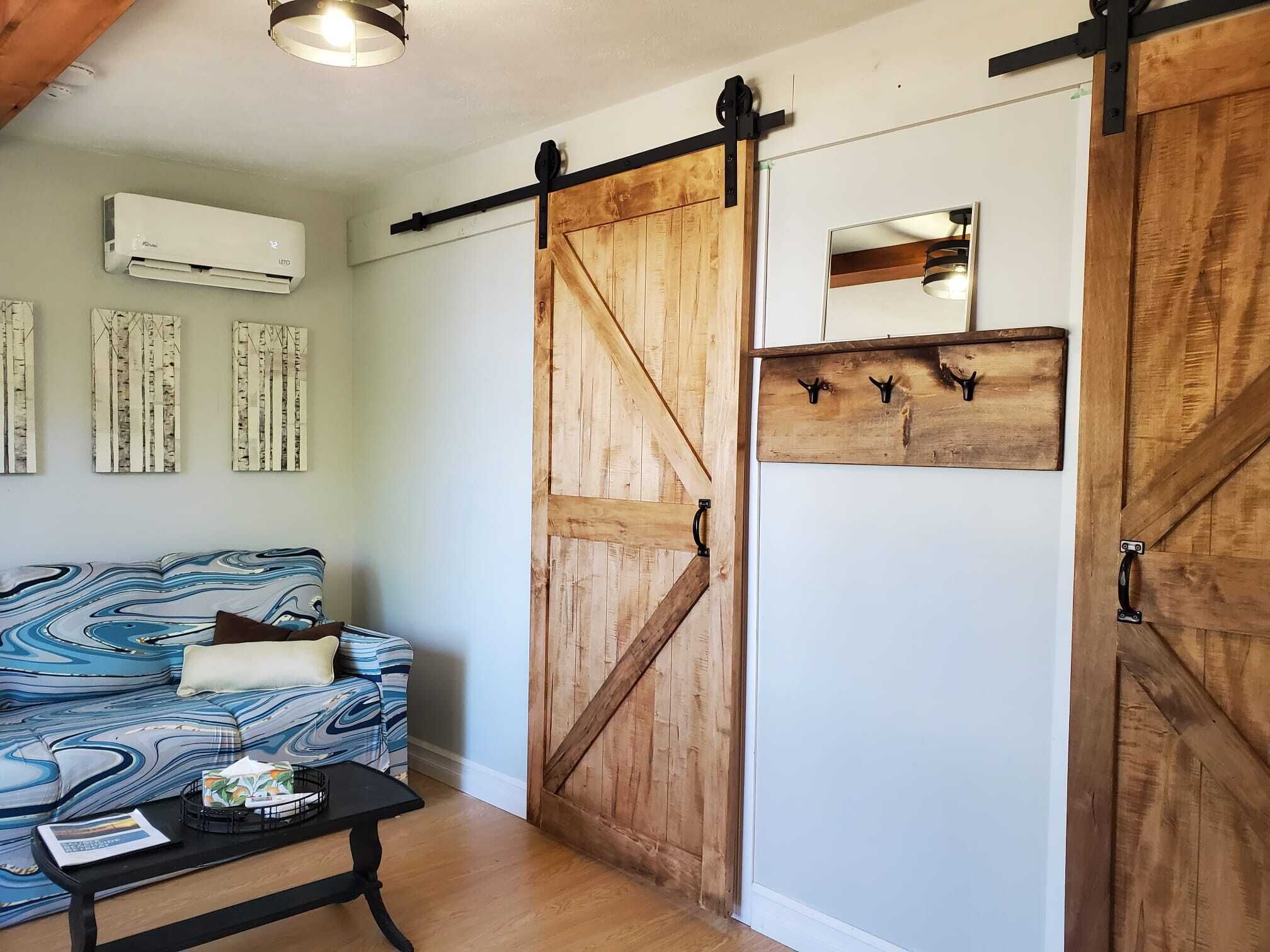 A room with a blue sofa, a black coffee table, a wooden sliding door, and a wall-mounted air conditioner.