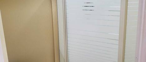 Un baño con ducha de vidrio, inodoro y piso de baldosas.