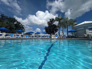 Ein Swimmingpool mit klarem, blauem Wasser, umgeben von blauen Sonnenschirmen und Liegestühlen.