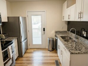 A compact kitchen with a stainless steel refrigerator, a granite countertop, and a sink. - Charming House Retreat Near Charleston (Charleston)