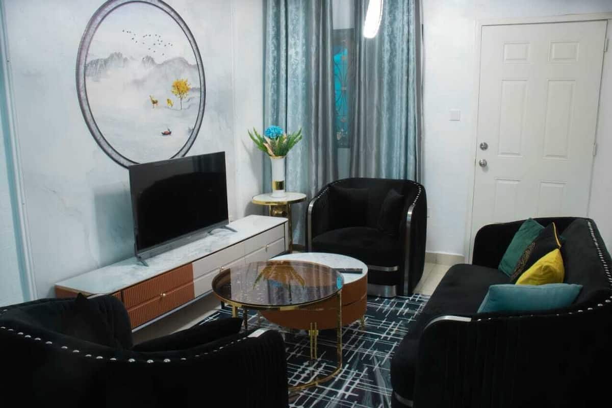 A modern living room with a flat-screen TV, a round coffee table, a sofa, and a chair.