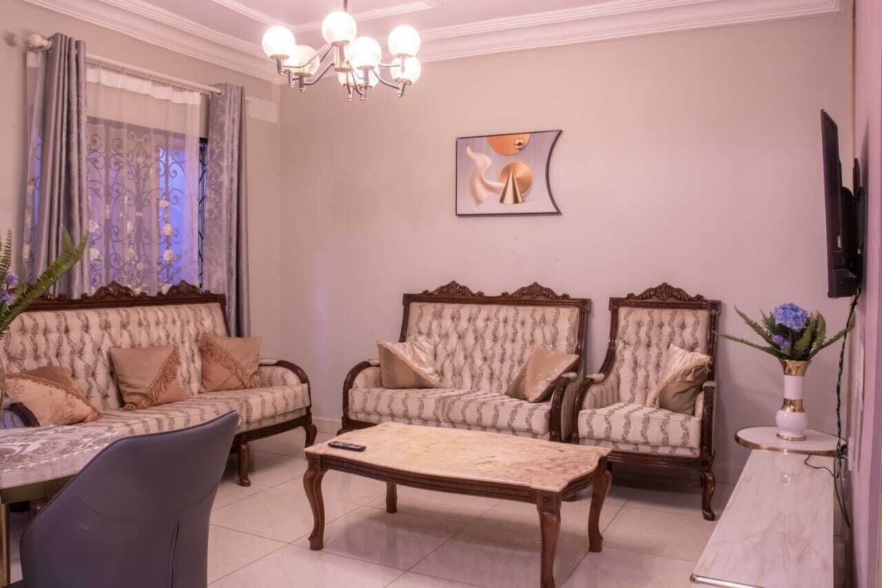 A living room with a sofa, two armchairs, a coffee table, a TV, and a painting on the wall.