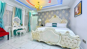 Ein luxuriöses Schlafzimmer mit einem großen Bett, einem Schminktisch und einer Kristallleuchtre.'