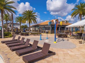 A poolside area with lounge chairs, a bar & grill, and palm trees. - Cozy Townhouse at Balmoral Resort (Haines City)