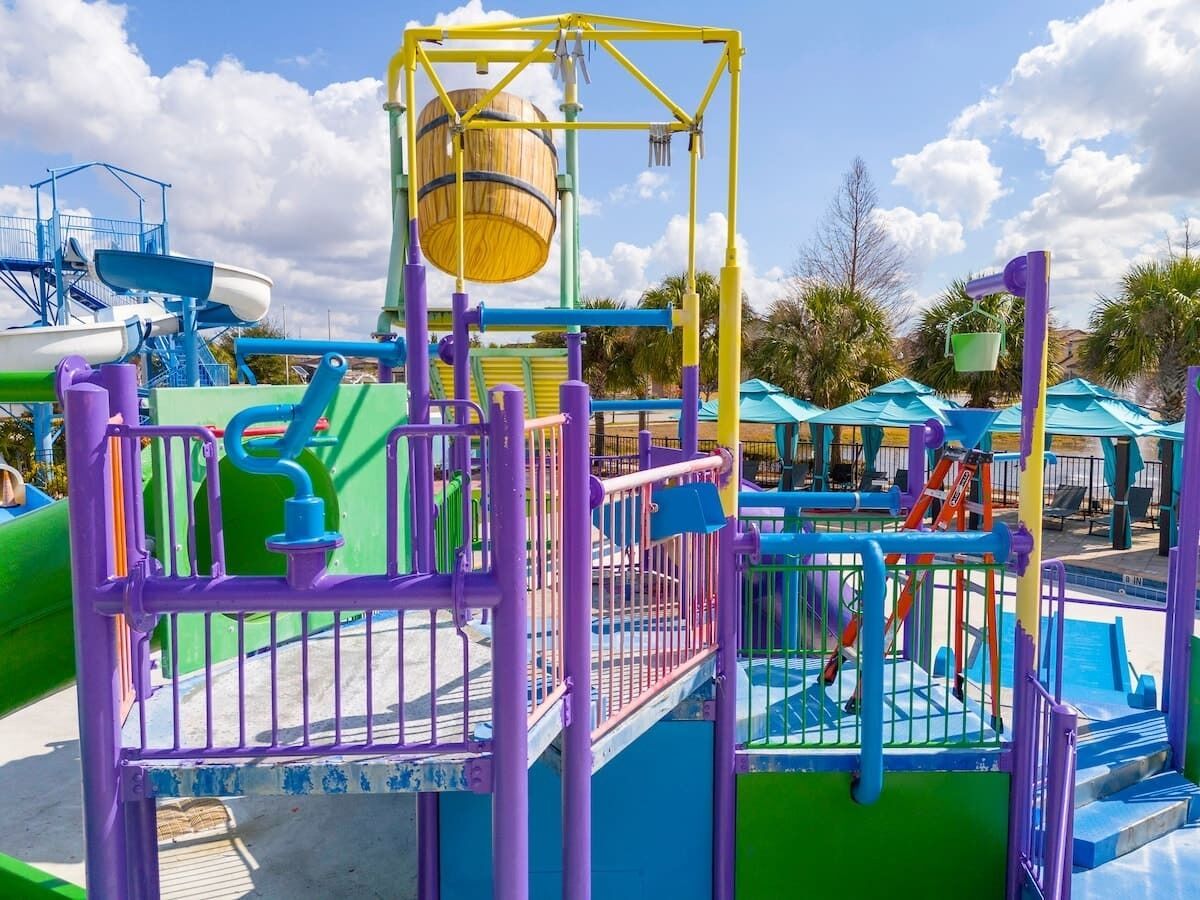 Een waterpark met een speelconstructie, glijbanen en een zwembad.