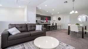Un salon moderne comprenant un canapé, une table basse et un coin repas avec des chaises et une table.