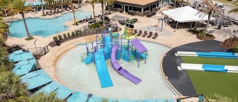 A pool area with multiple slides, lounge chairs, and palm trees.