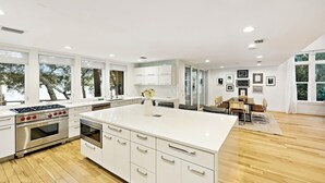 Una cocina moderna con armarios blancos, una isla grande y una zona de comedor con mesa y sillas.