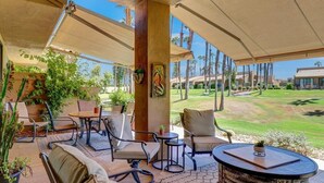 Un patio al aire libre con asientos, una mesa redonda y vistas a un campo de golf.