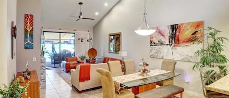 A spacious living area with a dining table, chairs, a sofa, and a ceiling fan.