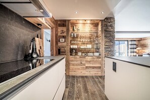 Eine moderne Küche mit einer Holzvertäfelung, einer Akzentwand aus Stein und einer schwarzen Arbeitsplatte.