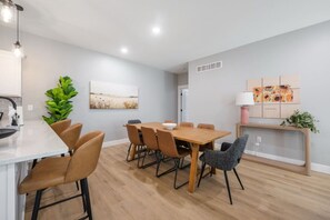 A modern kitchen with a dining area, wooden table, and chairs. - Family Home | Sleeps 8 | Walk to K-State (Manhattan)