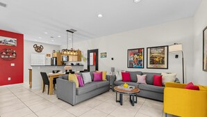 Una sala de estar moderna con un sofá gris, un sillón amarillo y un comedor con una mesa y sillas de madera.