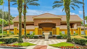 Entrada de hotel con un letrero que dice 'INCANTADA', un patio con palmeras y un jardín bien cuidado.