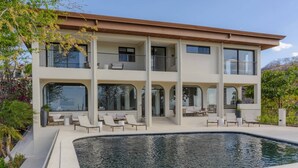 Uma casa de vários andares com piscina, área de estar ao ar livre e vista para a paisagem circundante.