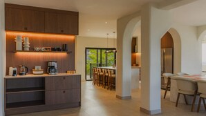 Cozinha moderna com eletrodomésticos embutidos, sala de jantar com balcão e vista para o exterior.