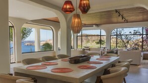 Uma sala de jantar com uma mesa grande, cadeiras e luminárias pendentes.